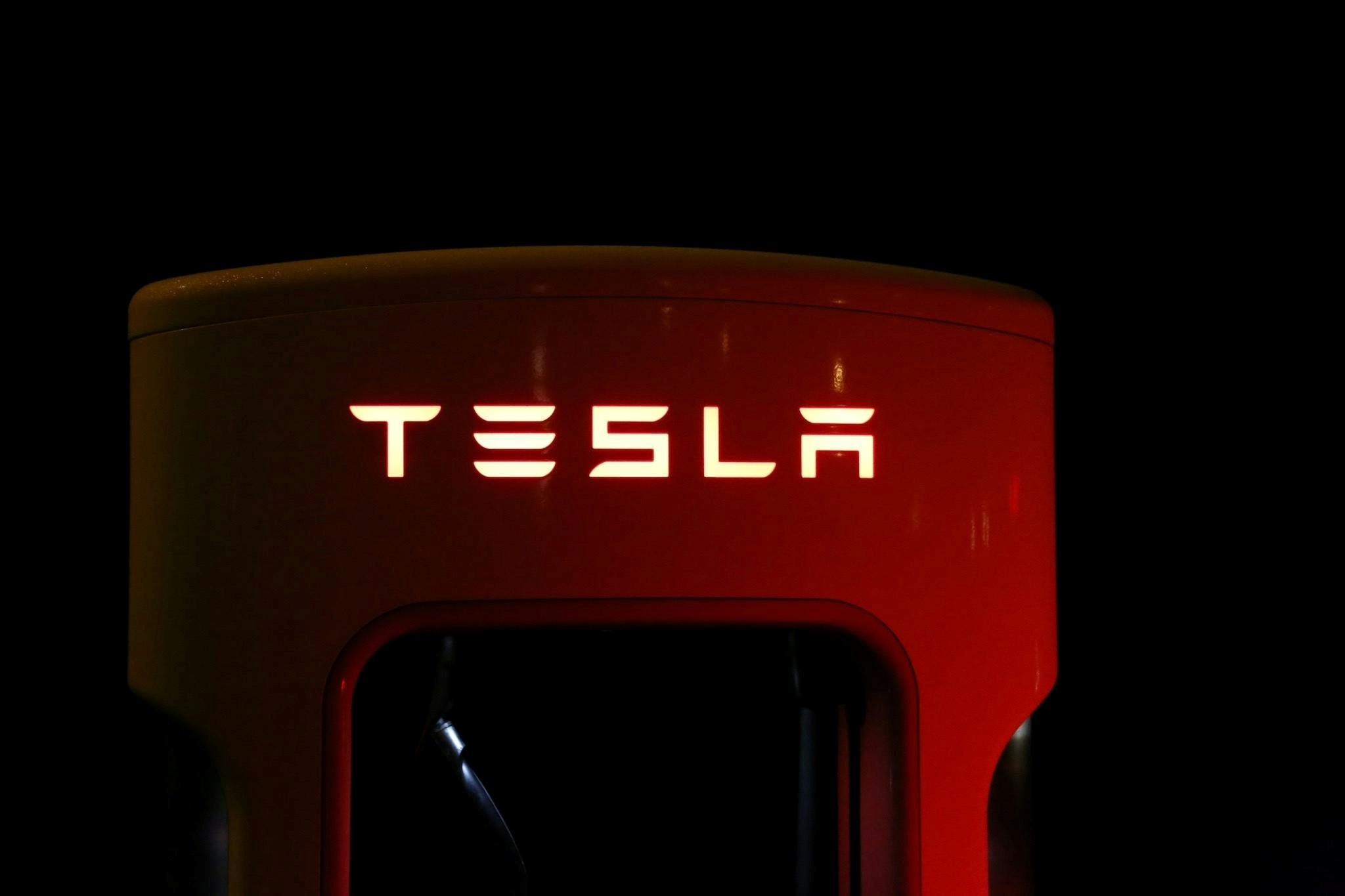 „Tesla“ logotipas ant įkrovimo stotelės.
