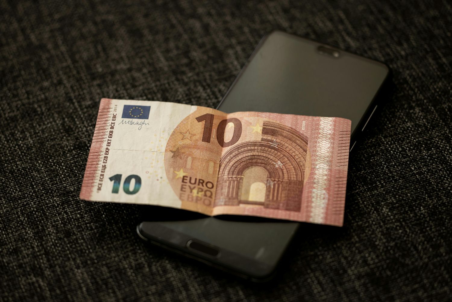 10 eurų banknotas ant telefono simbolizuoja mikro investavimą
