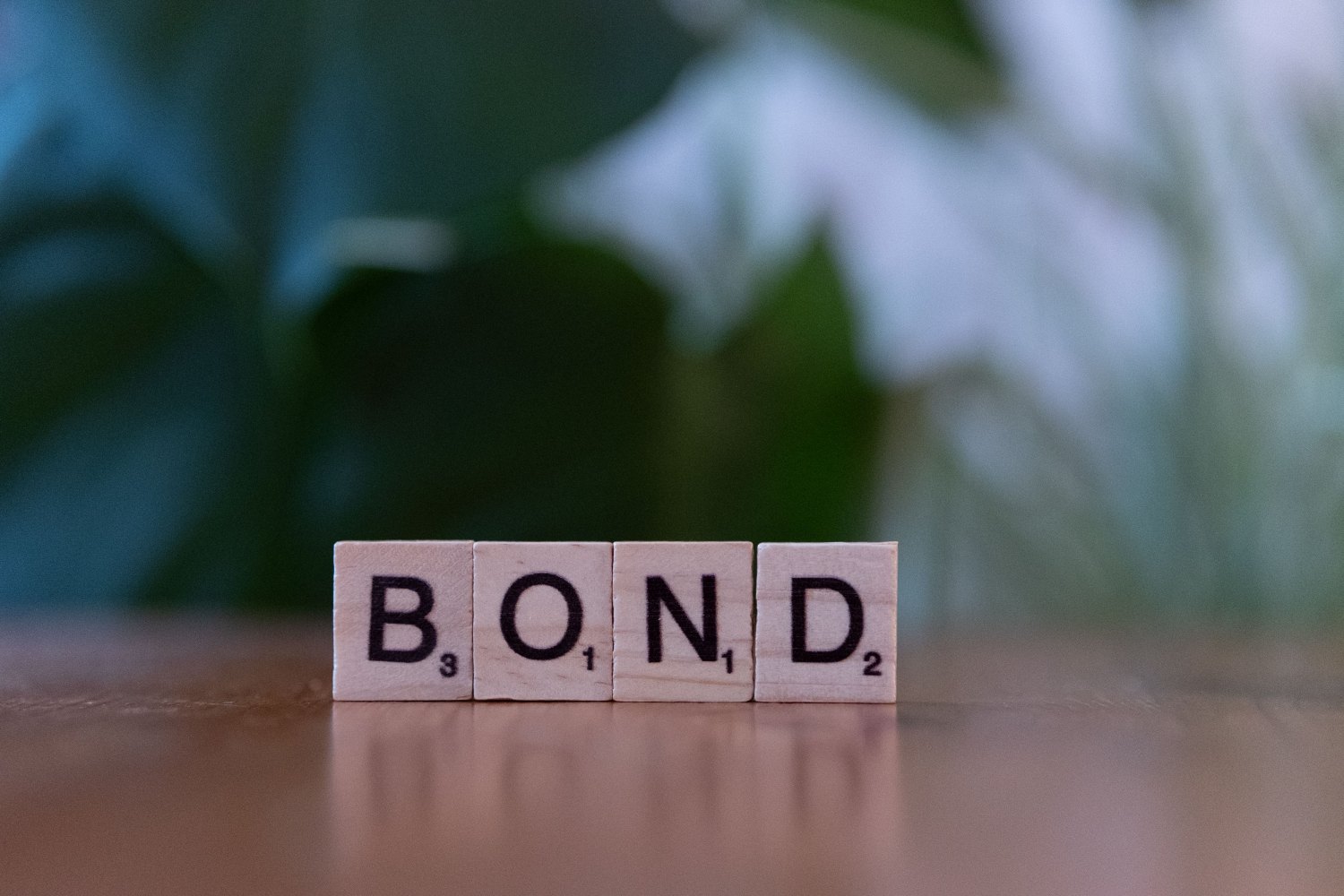 Medinės kaladėlės su užrašu „BOND“, simbolizuojančios investavimą į įmonių obligacijas.