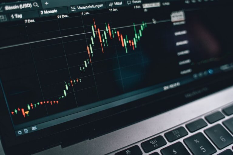 Nešiojamojo kompiuterio ekrane matomas kainos grafikas su žvakėmis, iliustruojantis tendencijos sekimo strategiją ir prekybą pagal rinkos kryptį.