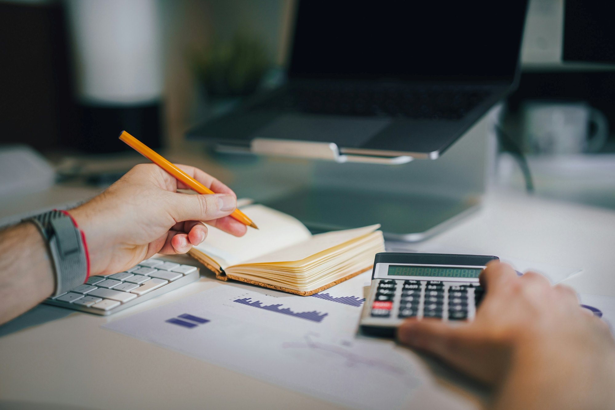 Žmogus skaičiuoja ir analizuoja finansinius duomenis, iliustruojančius investicijų mokesčių planavimą.