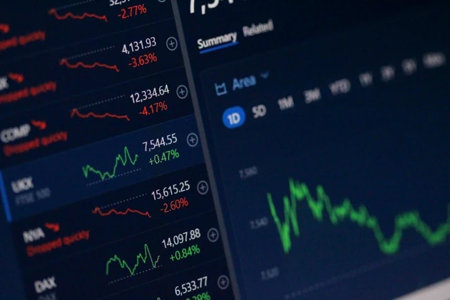 Investavimo platformos ekranas su akcijų ir rinkos kainų grafikais, iliustruojantis investavimą mažomis sumomis ir periodinį portfelio kaupimą.